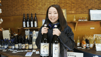 酒瓶を持ってにっこりほほ笑む長野県上田市・若林醸造の女性杜氏