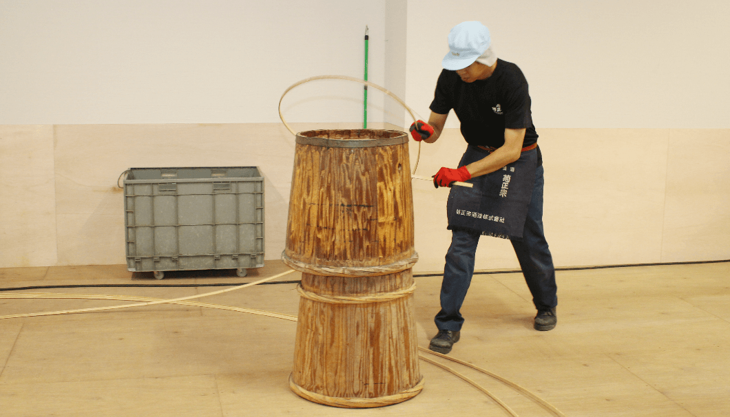 木樽に合わせて細く割った竹を巻く「箍巻き」の作業