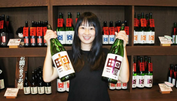 「中田屋」の瓶を掲げる佐藤酒造店の佐藤麻里子さん