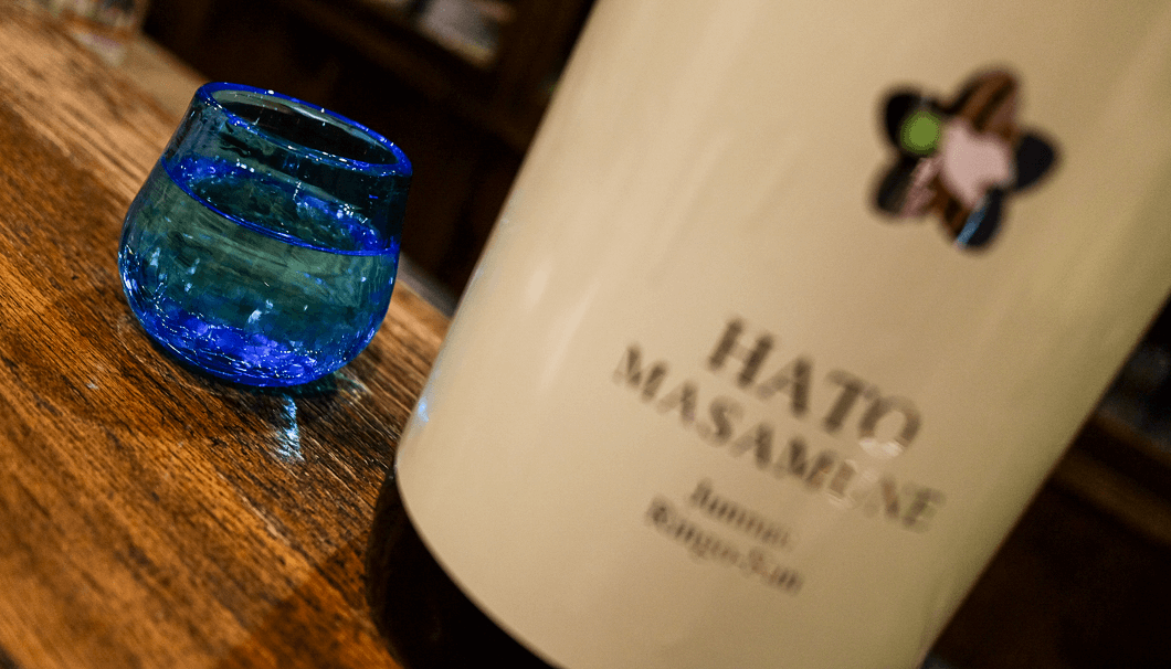 「鳩正宗 純米酒 リンゴ酸酵母仕込み」のボトルとグラスの写真