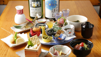 小鉢に入ったお料理と、日本酒のボトルがテーブルに並んだ写真