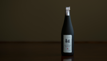 朝日酒造株式会社の新ブランド「継」、黒いボトルが1本立っている写真