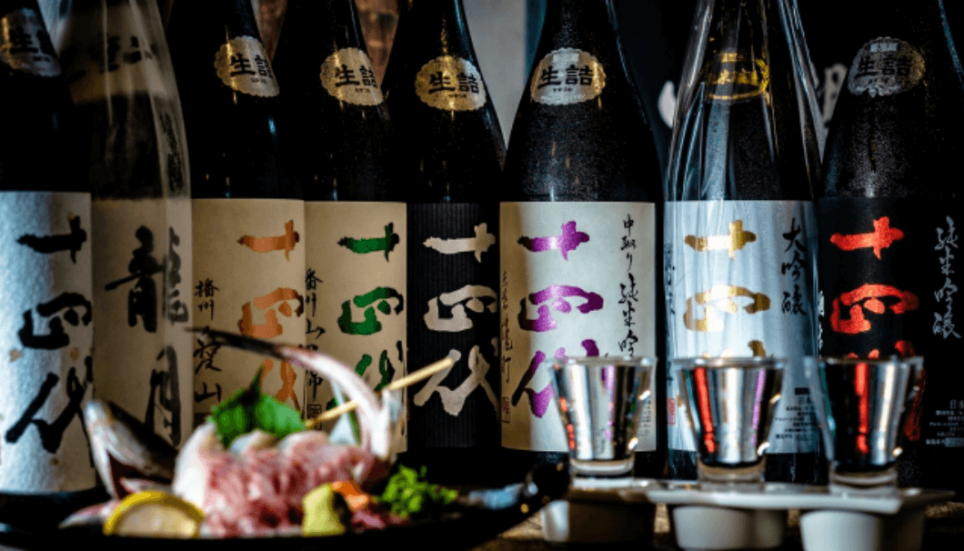 新鮮な魚介類を前に、十四代の日本酒が並んでいる写真