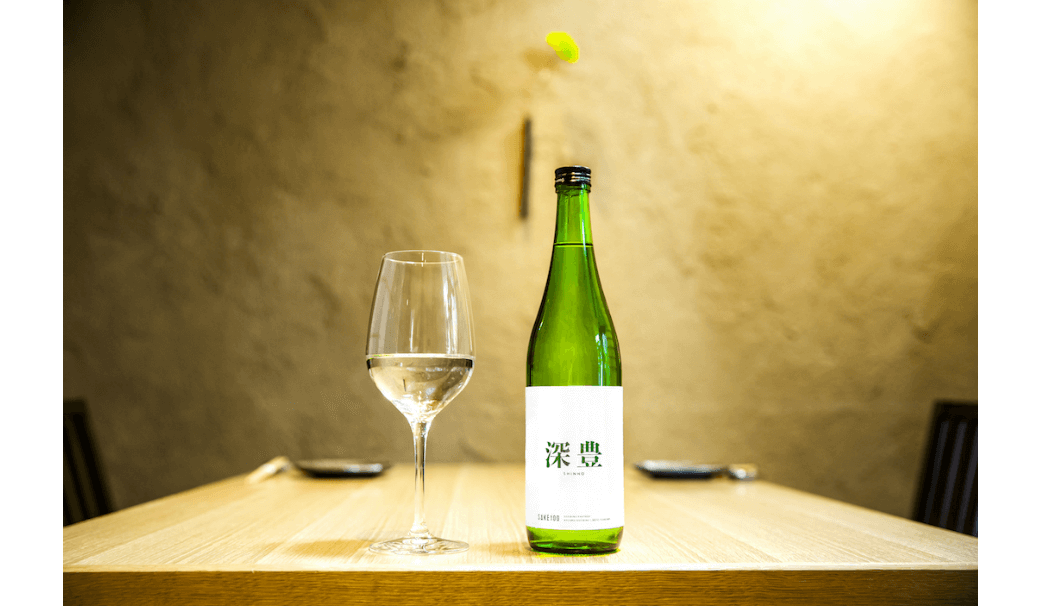 株式会社Clear(東京都渋谷区)が展開するプレミアム日本酒ブランド「SAKE100(サケハンドレッド)」の第2弾商品『深豊』のボトルとグラスの写真
