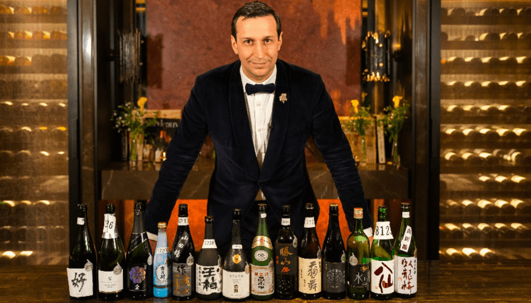 Kura Masuter　日本酒を前にして立っている男性の写真