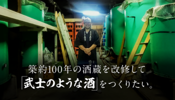 権田酒造の七代目蔵元が、タンクの前で笑顔の写真