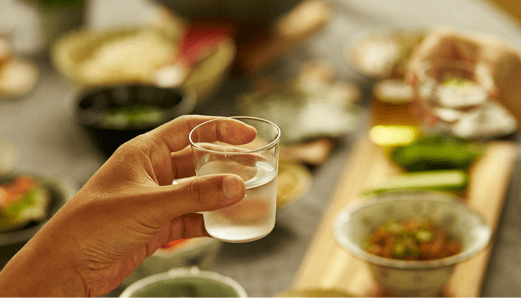 「沢の鶴 ためトク日本酒セミナー」のイメージ画像(料理を前に日本酒の入ったグラスを持つ手)